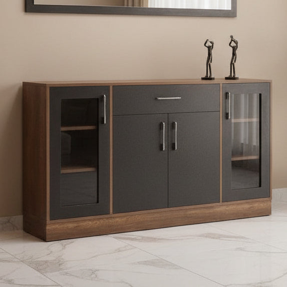 A modern sideboard cabinet with a dark charcoal black center and warm brown wood grain sides and top, featuring two glass-front cabinets with dark handles and a single drawer with a silver handle. It is styled in a room setting with a textured gray wall, a rectangular mirror, and a potted plant.