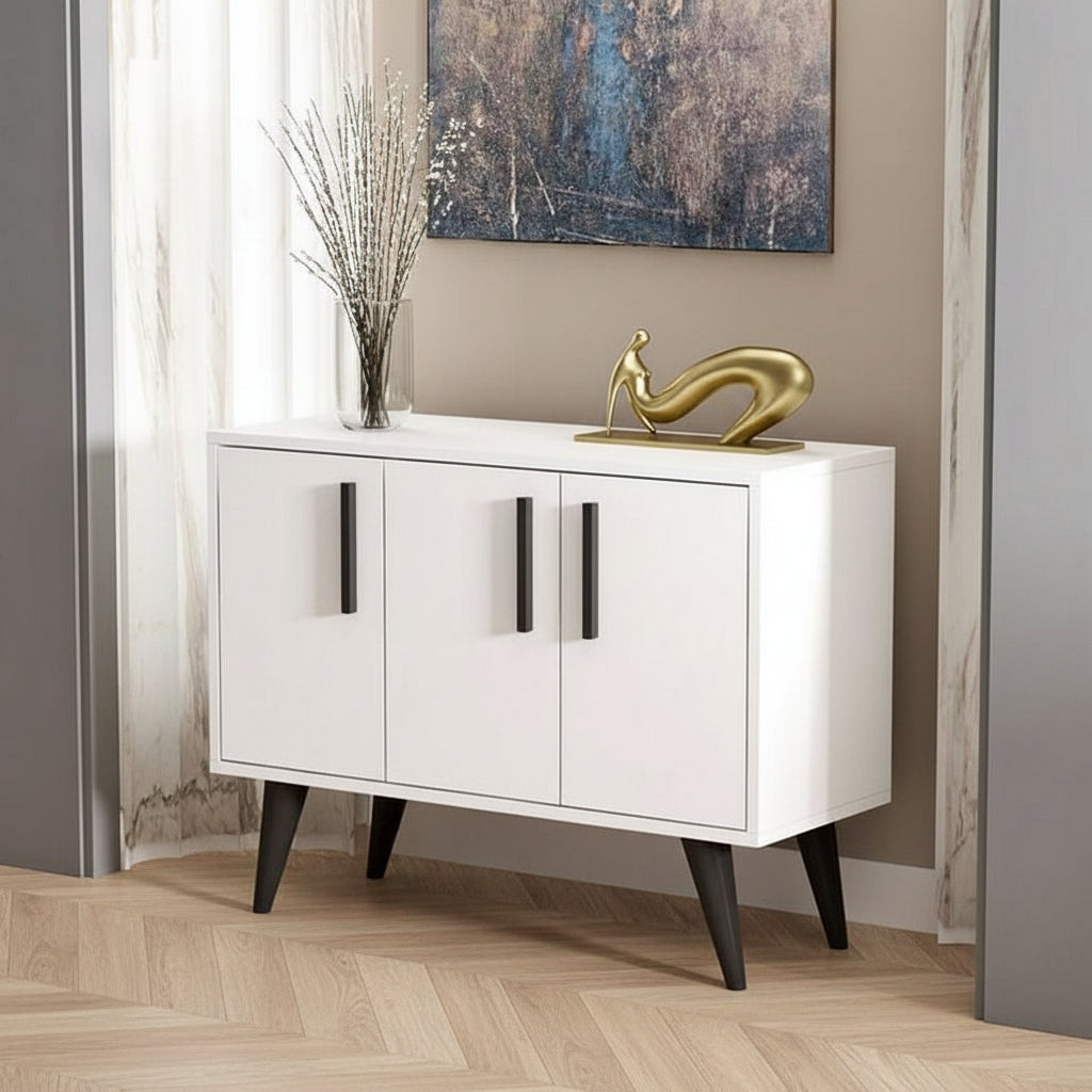 White sideboard with black legs in a room with a painting on the wall.