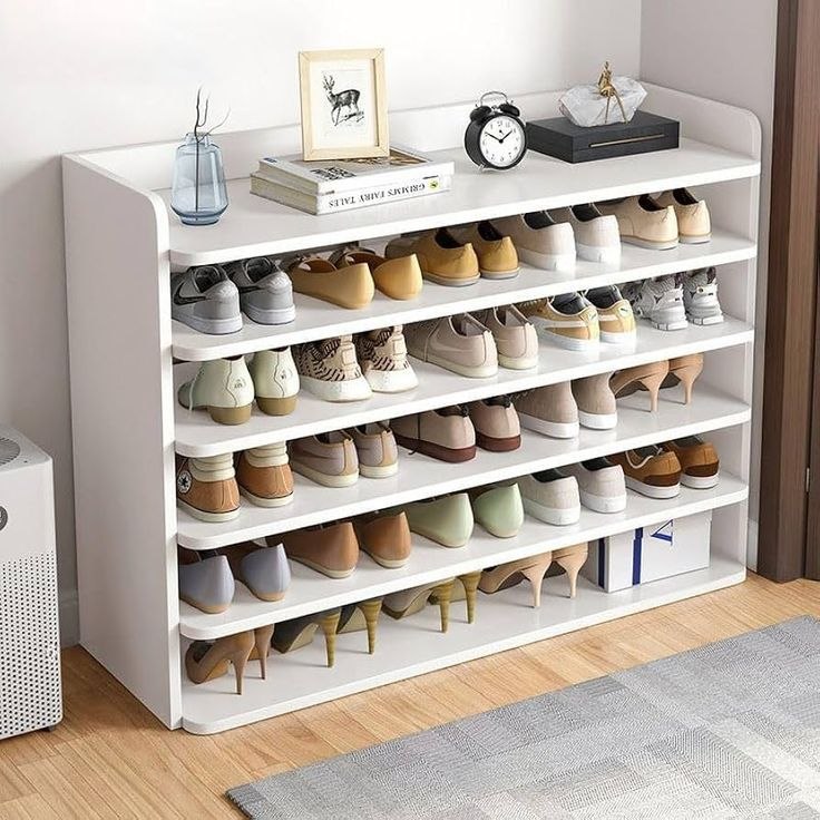 A white 5-tier shoe rack organizer filled with various casual, heeled, and flat shoes, styled in a home entryway setting with decorative items on top.