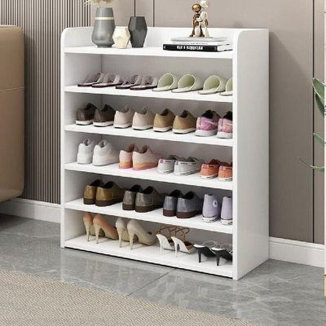 White shoe rack with various shoes on shelves in a room setting.