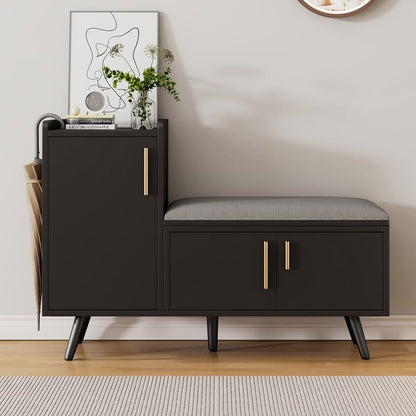 A modern dark brown entryway console cabinet with a matching bench seat, gold-tone handles, and black legs, styled in a minimalist room setting with a framed print and vase.