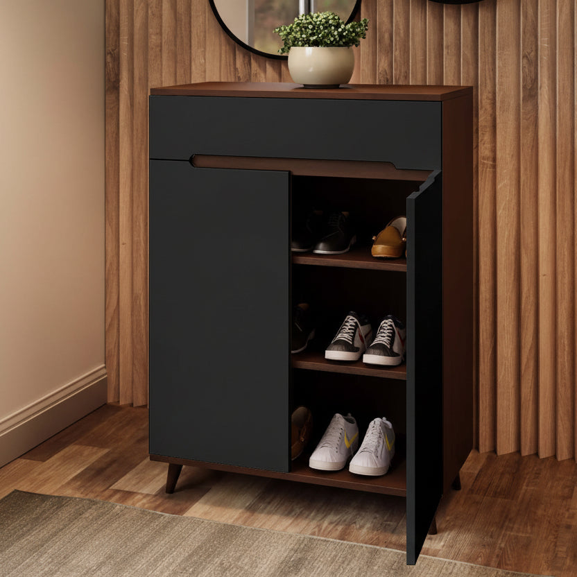 A modern shoe cabinet with a dark charcoal gray front and a medium brown wood-grain finish, shown with one door open to reveal shelves with shoes. The cabinet is set against a wooden slatted wall and wood floor, with a potted plant on top.