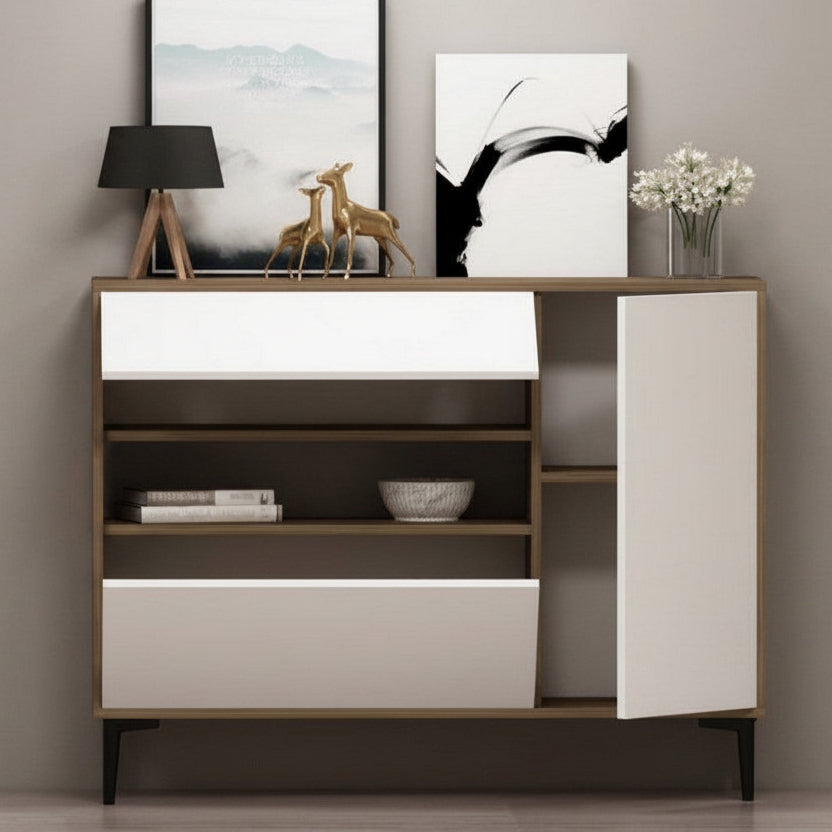 A modern wooden sideboard cabinet with white front panels, open shelves, and a side door, styled with a lamp, framed wall art, deer figurine, flowers, and books against a neutral gray wall.