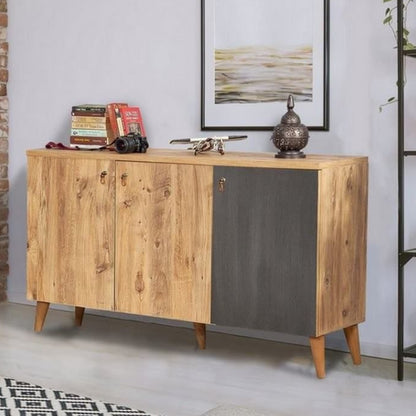 A rustic wooden sideboard cabinet with two light oak doors and one dark gray panel, styled in a modern room setting with a brick wall, shelving, and decorative items on top.